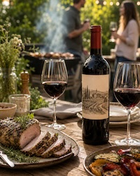 On an outdoor patio, a meal of grilled herb roast and vegetables served with red wine